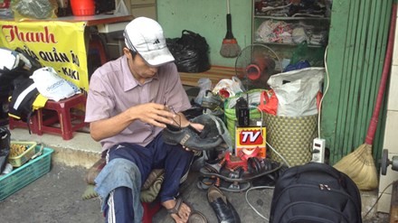 Anh Bình đang sửa giày cho một người bán vé số