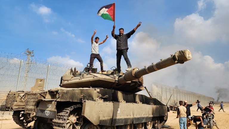 Người Palestine đứng trên một chiếc xe tăng của Israel bị phá hủy vào ngày 07/10. (Ảnh: Getty Images).