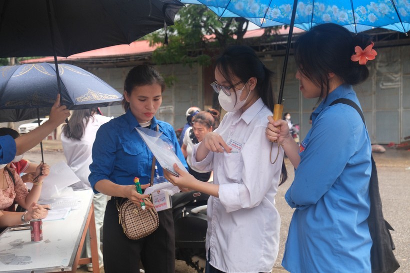 Lực lượng tình nguyện viên hỗ trợ thí sinh dưới cơn mưa sáng 27/6.