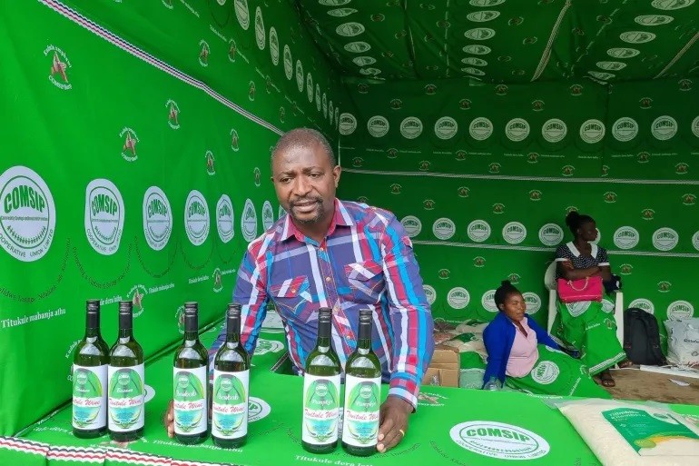 Một thành viên của Hợp tác xã Twitule bán chai rượu chuối tại hội chợ thương mại ở Blantyre, Malawi. Ảnh: COMSIP