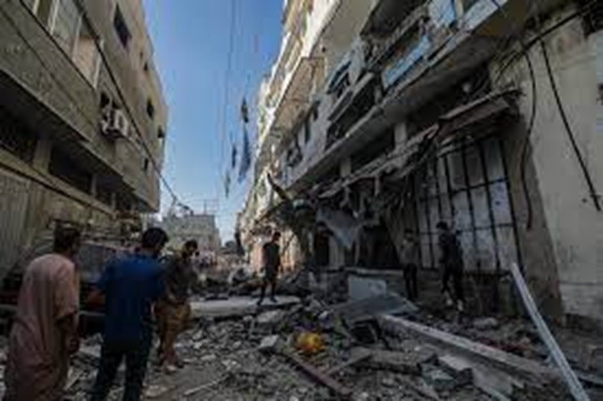Người dân địa phương đi qua những tòa nhà bị hư hại sau các cuộc không kích của Israel ở khu Al Zaitun thuộc thành phố Gaza hôm 7/11/2023