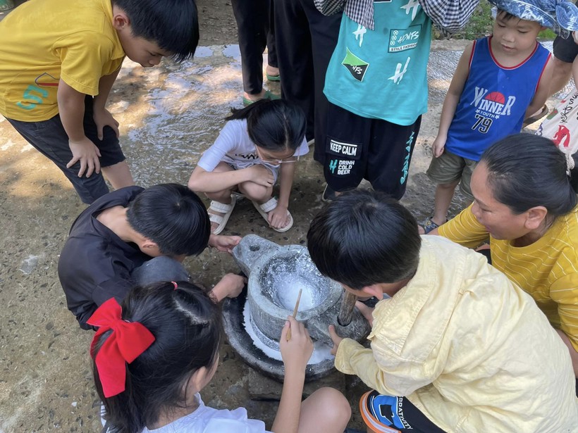 Trẻ em thành phố háo hức khi lần đầu sử dụng cối đá để xay bột làm bún, sợi mì Quảng. Ảnh: NVCC