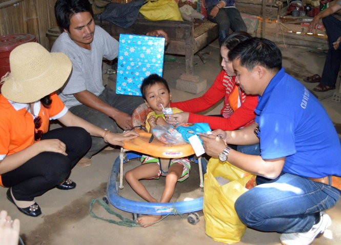 Thầy Sơn (bìa phải) cùng đồng nghiệp, bạn bè đến thăm một cháu nhỏ khuyết tật - Ảnh: B.D.