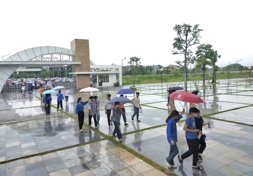 Các tình nguyện viên tiếp sức mùa thi nhiệt tình che ô cho thí sinh vào Hội đồng coi thi trường THPT Chuyên Hùng Vương.