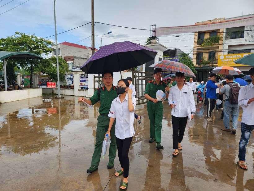 Tình nguyện viên tích cực hỗ trợ thí sinh khi trời mưa.