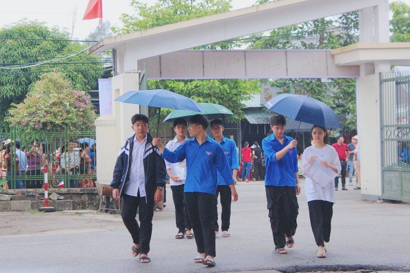 Tình nguyện viên che ô tránh mưa cho thí sinh vào phòng thi.