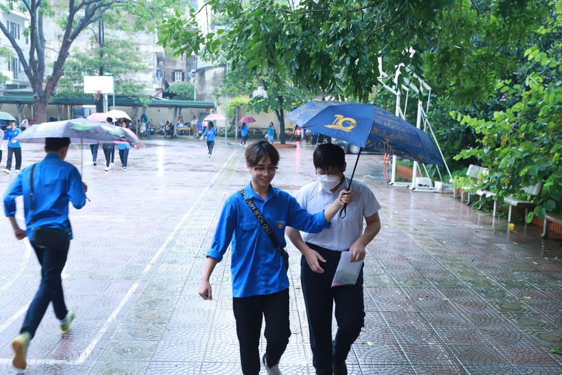 Lực lượng thanh niên thay nhau cầm ô che mưa cho thí sinh.