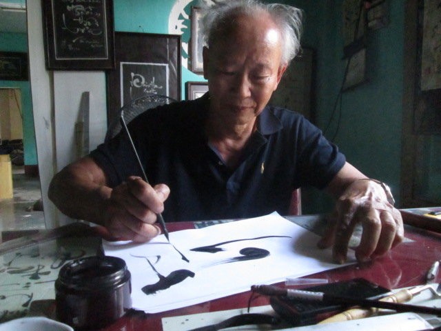 Ông đồ Vĩnh Thọ hướng dẫn cách đặt bút khi viết thư pháp

